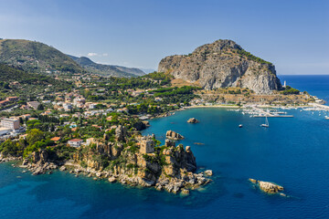 Obraz premium Aerial drone view of Scalette Beach in Cefalu, Sicily, Italy. the Tyrrhenian Sea, Capo Cefalu Lighthouse, rocky cliffs, Cefalu Harbor, and medieval castle ruins with scenic coastline panorama
