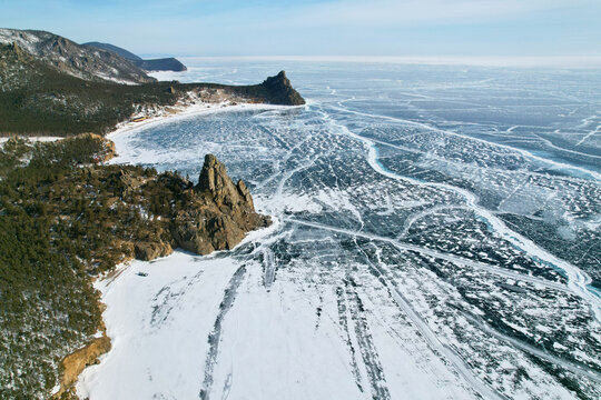 Lake Baikal in winter, aerial view. Beautiful view of Cape Kolokolny, Sandy Bay and a frozen lake, transparent ice with cracks. - Powered by Adobe