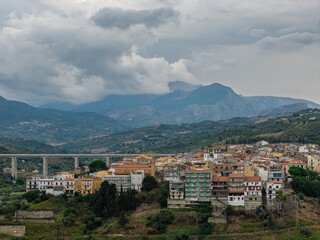 Obraz premium Aerial drone view of Campofelice di Roccella, a historic Sicilian village in Palermo,Sicily, Italy, featuring traditional stone houses, the Madonie Mountains, and the iconic highway viaduct