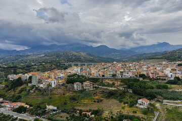 Fototapeta premium Aerial drone view of Campofelice di Roccella, a historic Sicilian village in Palermo,Sicily, Italy, featuring traditional stone houses, the Madonie Mountains, and the iconic highway viaduct
