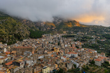Aerial drone view of Collesano Sicilian mountain town at sunset with Basilica San Pietro church and historic stone streets in the Madonie Mountains, Sicily, Italy. Old mountain town in Sicily
