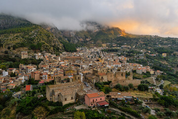 Aerial drone view of Collesano Sicilian mountain town at sunset with Basilica San Pietro church and historic stone streets in the Madonie Mountains, Sicily, Italy. Old mountain town in Sicily