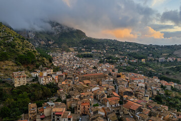 Aerial drone view of Collesano Sicilian mountain town at sunset with Basilica San Pietro church and historic stone streets in the Madonie Mountains, Sicily, Italy. Old mountain town in Sicily