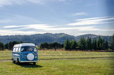 Portland, Oregon, USA - Sept. 30, 2025: A vintage blue van parked in a field parking lot for a festival event.