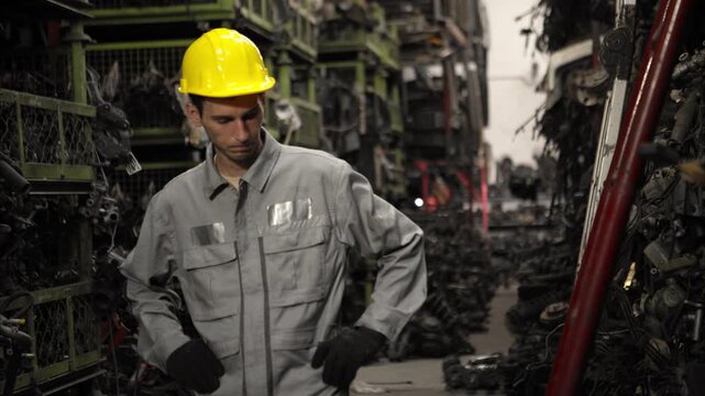 Tired industrial worker wearing safety uniform and gloves wiping sweat from his forehead after hard physical labor in a factory, representing fatigue and exhaustion at work