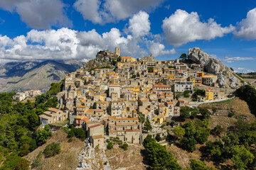 Fototapeta premium Aerial drone view of Sclafani Bagni, a small historic Sicilian mountain town perched on cliffs with panoramic views of Caltavuturo and rugged Madonie Mountains, Sicily, Italy.Small Village in Sicily