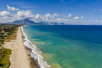 Fototapeta premium Aerial drone view of Lascari Beach, a scenic coastal area near the Madonie Mountains in northern Sicily, Italy, golden sand, turquoise Tyrrhenian Sea waters, and a peaceful Mediterranean landscape