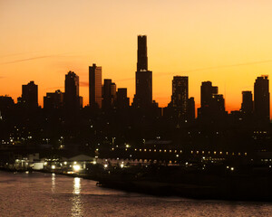 Golden sunlight rises over the Red Hook waterfront in Brooklyn, illuminating warehouses, cranes, and calm harbor waters with a warm glow as the city slowly awakens to a new day.
