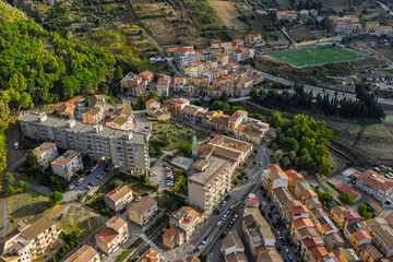 Fototapeta premium Aerial drone view of Collesano Sicilian mountain town at sunset with Basilica San Pietro church and historic stone streets in the Madonie Mountains, Sicily, Italy. Old mountain town in Sicily