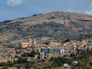 Fototapeta premium Aerial drone view of Petralia Sottana, a historic Sicilian mountain town surrounded by scenic hills and the Madonie Mountains, featuring traditional stone houses and panoramic landscapes, Sicily Italy