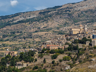 Obraz premium Aerial drone view of Petralia Sottana, a historic Sicilian mountain town surrounded by scenic hills and the Madonie Mountains, featuring traditional stone houses and panoramic landscapes, Sicily Italy