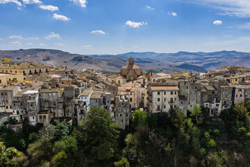 Obraz premium Aerial drone view of Polizzi Generosa, a picturesque Sicilian mountain town perched on rocky cliffs showcasing traditional stone buildings and panoramic views of the Madonie Mountains, Sicily, Italy