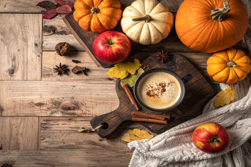 Rustic autumn still life with pumpkins, apples, coffee, and cinnamon on a wooden board &mdash; rich fall ambiance.