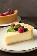 Piece of delicious cheesecake with fresh berries and mint on wooden table, closeup