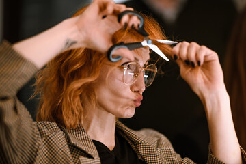 Fototapeta premium Woman playfully posing with scissors while showing off her stylish haircut in a creative space during daytime