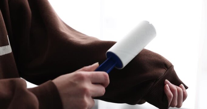 Woman using lint roller at home, closeup