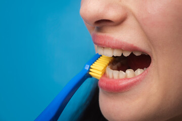 Dental treatment. Teeth examined at dentists. Healthy woman teeth. Ideal teeth. Dental tools white tooth. Girl holding a blue toothbrush while brushing her teeth, emphasizing proper dental care