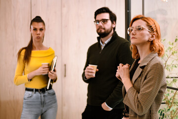 Three professionals engaged in discussion during a casual meeting at a modern office space with warm lighting and a relaxed atmosphere