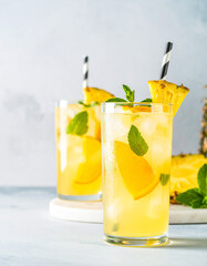 Two glasses of pineapple juice with a straw in each