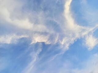 Fototapeta premium The beauty of the blue sky decorated with a unique spread of white clouds resembling flying birds and swirling winds in the afternoon... 
