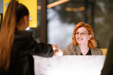 Friendly interaction at a modern reception desk during the day with smiling staff member assisting a visitor