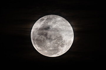 The Harvest Moon supermoon rises in the cloud covered sky