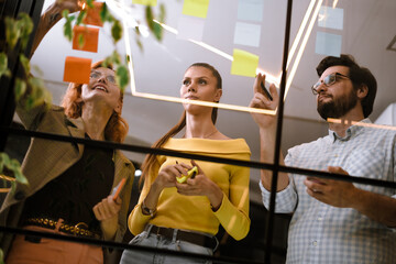 Team collaborating on project with sticky notes in modern office during afternoon meeting