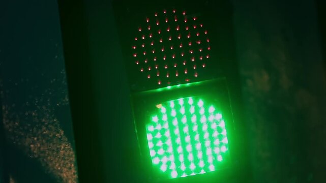 Traffic light changing from red to green at night in city street, LED bulbs glowing as signal transitions, symbolizing permission to go and urban traffic flow control
