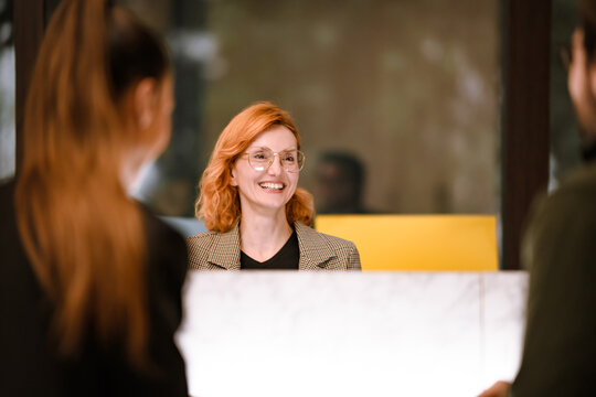 Friendly receptionist greets clients with a warm smile at a modern office during the day, creating a welcoming atmosphere for visitors