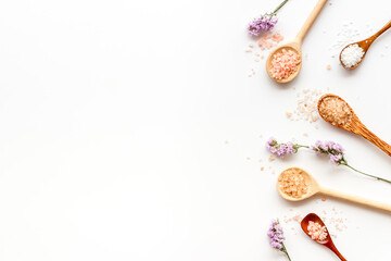 Obraz na płótnie Canvas Beauty spa therapy cosmetics and wellness flat lay - sea salt in many spoons with flowers, top view