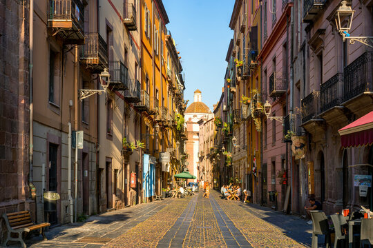 Bosa street featuring vibrant buildings leading to a church dome in Sardinia, Italy