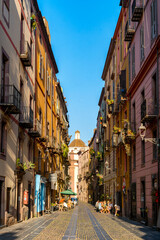 Bosa street featuring vibrant buildings leading to a church dome in Sardinia, Italy