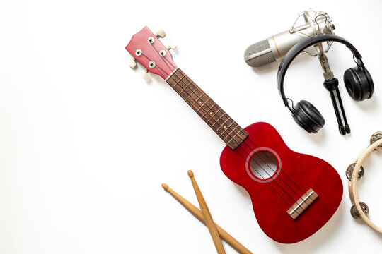 Recording music in a studio. Musical instruments for band - small guitar, drumsticks and tambourine - with studio microphone - Powered by Adobe
