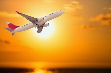 Airplane flying in bright beautiful sky at sunset