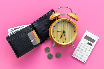 Black wallet with money cash bank card and alarm clock. Time to pay taxes or credit concept