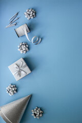 Holiday festive party flat lay with silver carnaval caps and cake candles, top view. Gift box and streamers on blue background