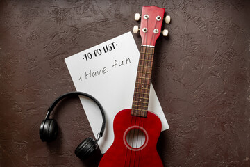Naklejka premium Small guitar ukulele on To do list with words Have fun. Musical instruments, top view