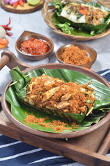 Grilled rice with shredded chicken and spiced grated coconut, wrapped in banana leaves, a traditional Indonesian dish