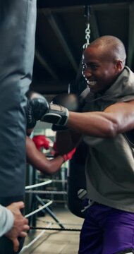 Punching bag, personal trainer and fitness with men in gym for combat sports, martial arts and workout. Self defense exercise, mma training and boxer with people in club for coaching and fight