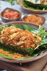 Grilled rice with shredded chicken and spiced grated coconut, wrapped in banana leaves, a traditional Indonesian dish