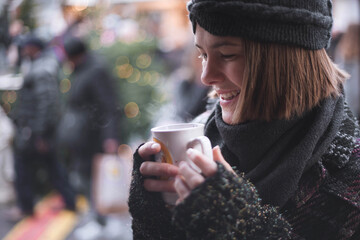 Headshot of beautiful young woman, while going to drink mulled wine out of cup on traditional...