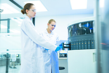 In a future smart lab, scientists load a 'lab-on-a-chip' microfluidic device into an analyzer, following a dynamic protocol on a tablet that is being optimized in real-time by an AI.