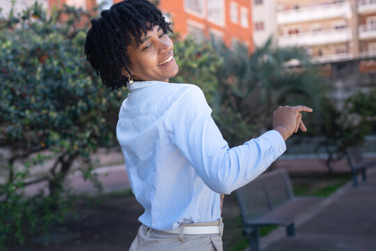 Beautiful, happy black woman with dreadlocks dancing in a park.