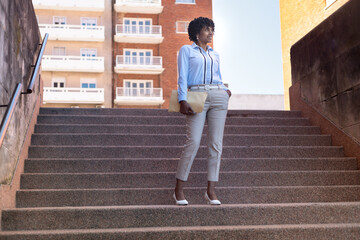 Confident businesswoman standing on city stairs looking ahead