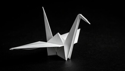 Elegant white origami crane sculpture poised on a dark surface, showcasing intricate folds and artistry