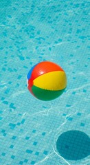 A colorful beach ball floats on the surface of a bright blue swimming pool.