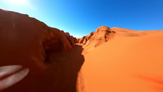 Dynamic drone shot flying forward through a winding canyon sculpted by towering red sand dunes on a bright day landscape, drone shot, patterns