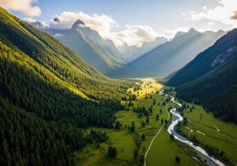 Sunlight illuminates a lush green valley with a winding river and majestic mountains