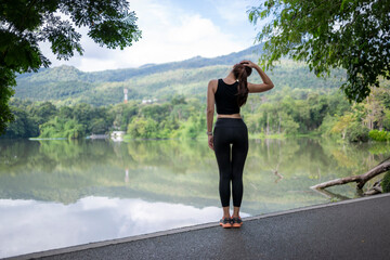 Woman stretching neck outdoors near lake and mountains