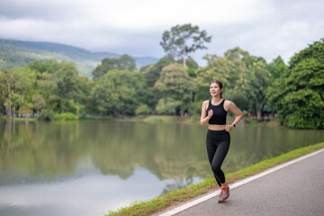 Asian woman jogging at park lake for fitness